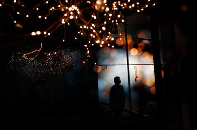 Silhouette people standing by illuminated lights at night