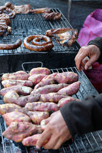 Cropped hands of person preparing food on barbecue grill