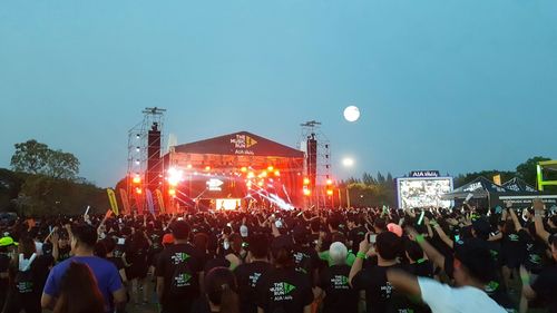 Crowd at music concert against sky at night