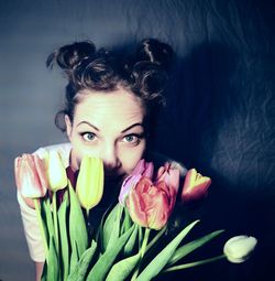 High angle portrait of young woman with colorful tulips by wall