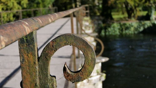 Close-up of rusty pipe by railing against lake