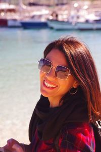 Portrait of smiling young woman wearing sunglasses at beach