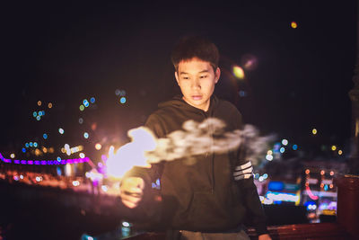 Man holding firework in illuminated city at night