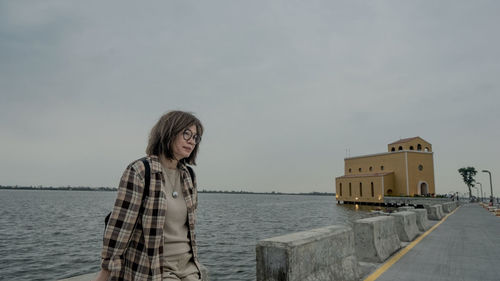 Portrait of young woman standing against sky