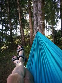 Low section of woman sitting at tent in forest