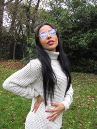 Beautiful young woman wearing hat standing against plants