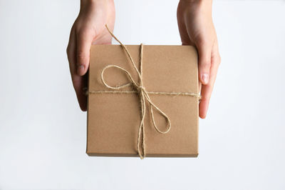 Cropped hand of woman holding gift against white background