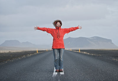 Woman standing in the middle of the road with arms stretched out