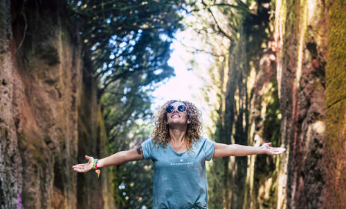 Woman with arms outstretched standing amidst trees