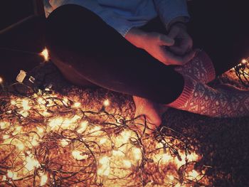 Low section of man sitting by illuminated lights