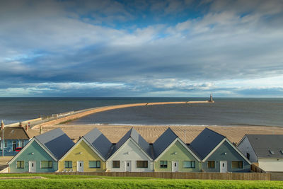 Houses by sea against sky