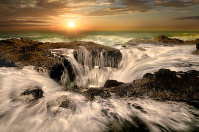 Scenic view of waterfall against sky during sunset