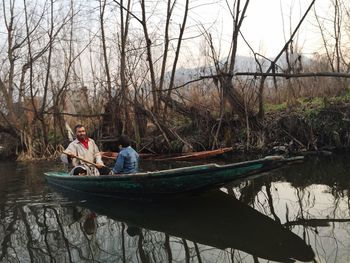 People sitting by lake against trees