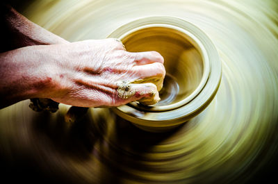 Hands of potter working on spinning wheel at workshop