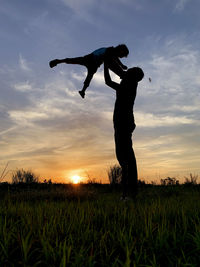 Silhouette man standing on field against sky during sunset