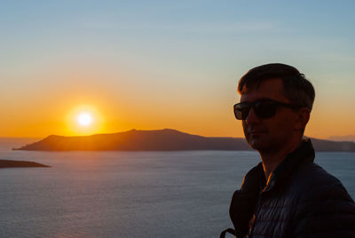 Silhouette of a man's head and shoulders in the background of a sunset in santorini, greece