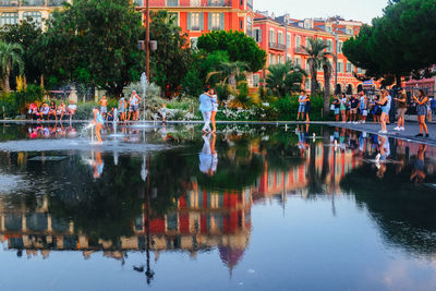 Reflection of trees in lake against buildings in city