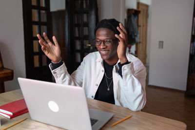 Smiling optimistic african american man waving hand having video call in laptop with friends