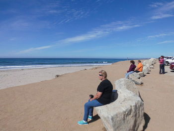 People sitting on beach against blue sky