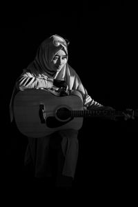 Man holding guitar against black background