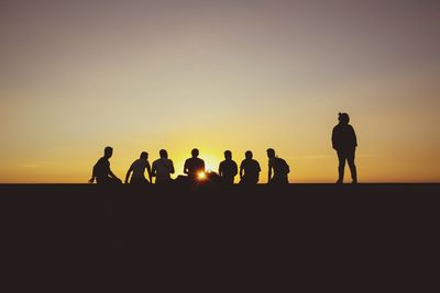 Silhouette people against orange sky