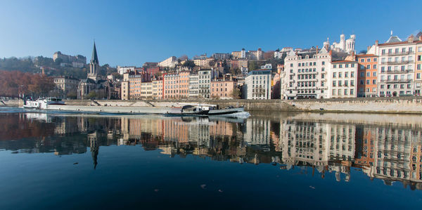 Reflection of buildings in city against clear sky