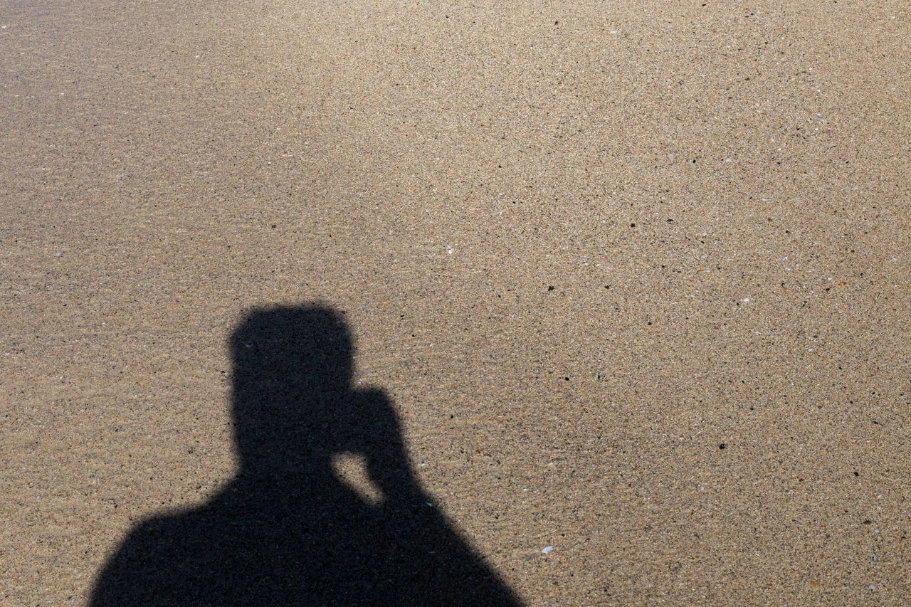 shadow, sunlight, sand, land, high angle view, beach, focus on shadow, nature, day, lifestyles, leisure activity, men, road surface, standing, asphalt, two people, outdoors, togetherness, floor, adult, footprint