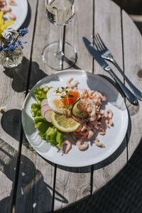 Prawn sandwiches and glass of white wine on table