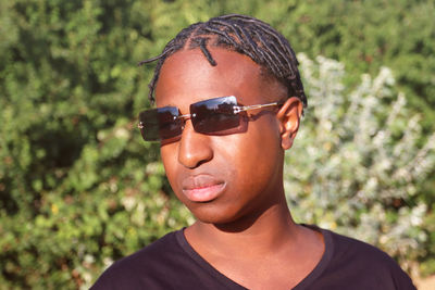 Portrait of young man wearing sunglasses against trees