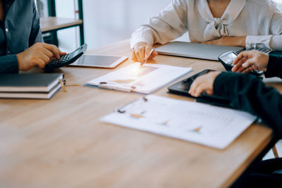 Midsection of man using mobile phone while sitting on table