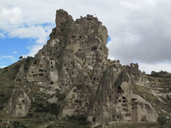 Ruins of rock formations against cloudy sky