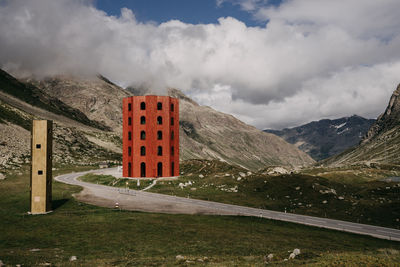 Built structure on field by mountains against sky