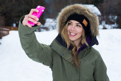 Girl in winter coat takes picture with cell phone