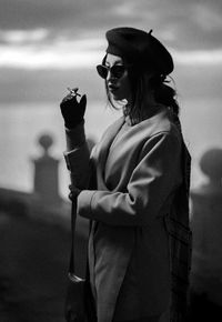 Woman holding cigarette while standing outdoors