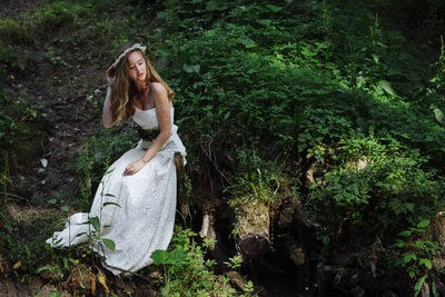 Beautiful woman in white dress sitting at lakeshore