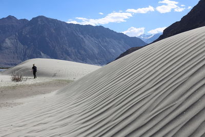 Rear view of man on snowcapped mountains against sky