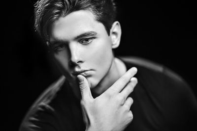 Close-up portrait of young man against black background