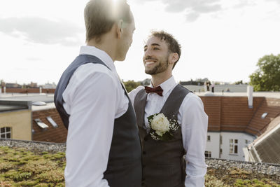 Loving gay couple looking at each other while standing on rooftop
