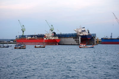 Fishing boats in sea against sky