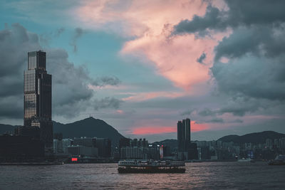 Scenic view of sea by buildings against sky during sunset