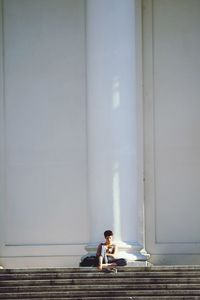 Man looking at camera while sitting on wall