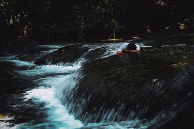 Man surfing on river flowing in forest