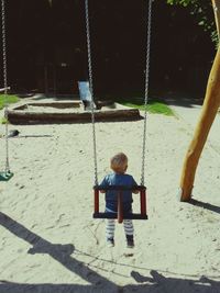 Rear view of boy on swing at playground