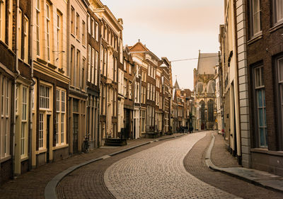 Empty road amidst buildings in city