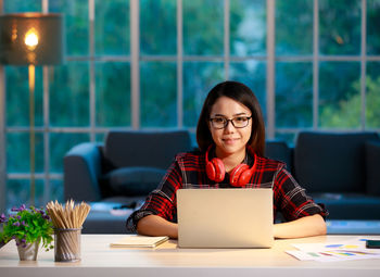 Portrait of young woman using phone while sitting on table