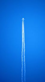 Low angle view of airplane flying against clear blue sky