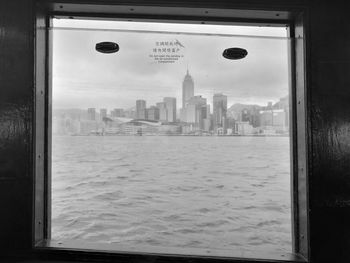 Cityscape by sea against sky seen through window