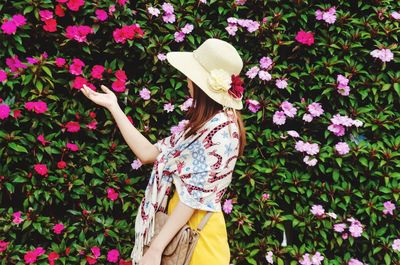 Woman standing by pink flowering plants