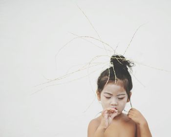 Shirtless girl with plants in hair against white background