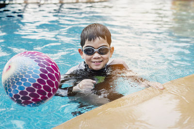 Asian happy kid playing slider in swimming pool